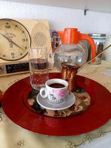 - un plateau rouge avec une tasse de café et une horloge dans l'établissement GuestHouseMantho, à Gjirokastër