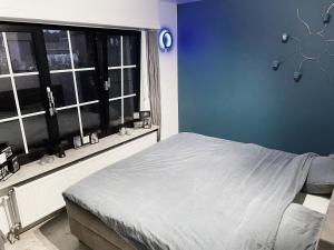 um quarto com uma cama com uma parede azul e uma janela em Relax em Kasterlee