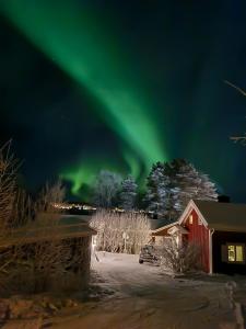 Eine Aurora scheint in den Himmel über einer roten Scheune in der Unterkunft Arctic Circle Cabin in Överkalix