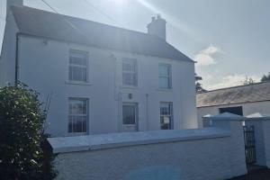 a white house with a fence in front of it at Alpaca farm 3 bed farmhouse THE ALPACA PLACE in Dromara