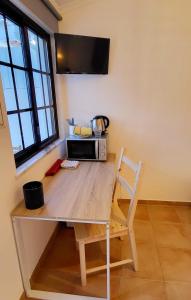 einen Tisch mit einer Mikrowelle und einem Stuhl in einem Zimmer in der Unterkunft Cantinho de Milfontes Jacuzzi in Vila Nova de Milfontes