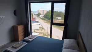 Un dormitorio con una cama y una ventana grande. en Beach apartments Ema, en Kranevo