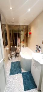 a bathroom with a tub and a toilet and a sink at private room with free parking close to lake side in West Thurrock