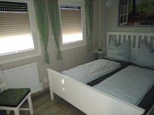 1 Schlafzimmer mit einem weißen Bett und 2 Fenstern in der Unterkunft Tiny Bungalow Visselhövede in Visselhövede