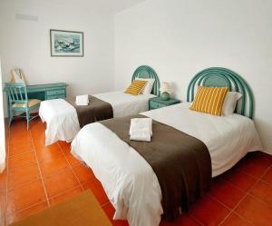 a room with two beds and a chair at Casa das Laranjeiras in Vale de Figueira
