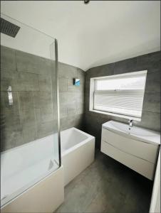 La salle de bains est pourvue d'une baignoire blanche et d'un lavabo. dans l'établissement Mark Road Villa, à Oxford