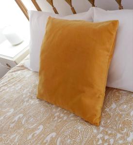 a yellow pillow sitting on a bed with two pillows at Casa das Laranjeiras in Vale de Figueira