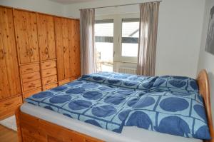 ein Schlafzimmer mit einem Bett mit blauer Decke und einem Fenster in der Unterkunft Zur angenehmen Gegend in Annweiler am Trifels