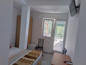 Vila Grozdanoski في Konjsko: غرفة نوم بسرير ومكتب ونوافذ