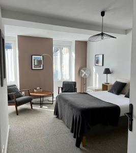 um quarto com uma cama, uma secretária e cadeiras em Flor du Mont Gîte em Pontorson