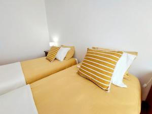 a bedroom with two beds with yellow and white pillows at Casa das Laranjeiras in Vale de Figueira
