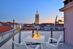 a white table and chairs on a balcony with a clock tower at Sea Gate Studio in Zadar