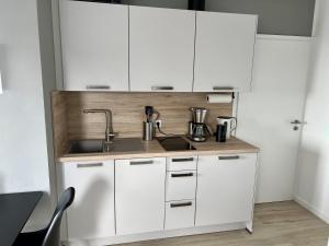 una cocina con armarios blancos y fregadero en PANORAMA - Exklusives Apartment an der Promenade mit Dachterrasse & Rheinblick, en Emmerich