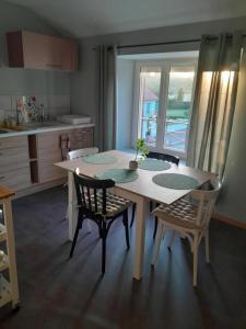 eine Küche mit einem Tisch und 2 Stühlen sowie eine Küche mit einem Fenster in der Unterkunft Gîte du capitaine in Maranville