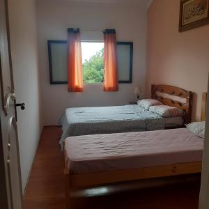 a bedroom with two beds and a window with orange curtains at Embu Manacás da Serra in Embu