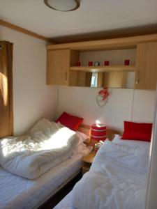a bedroom with two beds and a table with a lamp at Melody Brooks Caravan Park Caravan number 22 in Portknockie