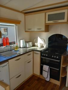 a small kitchen with a stove and a sink at Melody Brooks Caravan Park Caravan number 22 in Portknockie