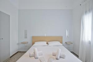 Dormitorio blanco con cama blanca y almohadas blancas en Athina, en Atenas