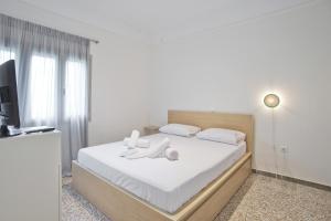 een slaapkamer met een bed met witte lakens en een televisie bij Athina in Athene