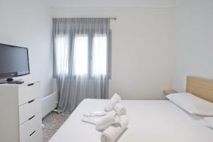 a white room with a bed with a tv and towels at Athina in Athens