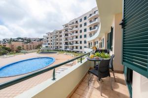 een balkon met een zwembad en een tafel en stoelen bij Sarah's Apartment by GALMI in Caniço