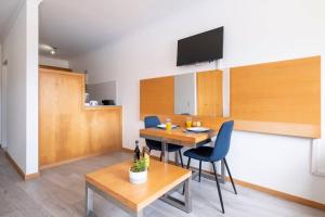 een woonkamer met een tafel, stoelen en een televisie bij Sarah's Apartment by GALMI in Caniço