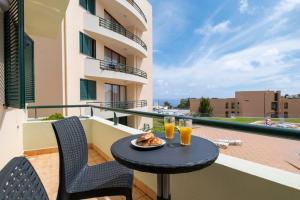 een tafel op een balkon met 2 glazen sinaasappelsap bij Sarah's Apartment by GALMI in Caniço