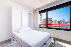 Cette chambre blanche dispose d'un lit et d'une fenêtre. dans l'établissement Loix Mar 11-E Apartment Levante Beach, à Benidorm