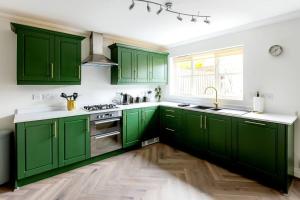 a green kitchen with white walls and wooden floors at Luxury 5 Bed house in the City, includes parking & EV point in Norwich