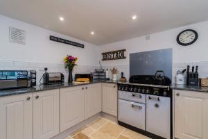 cocina con fogones y reloj en la pared en Jessamine: Restored fisherman's cottage close to Looe's harbour, en Looe 41 fotos más