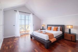 a bedroom with a large bed with orange pillows at Villa Sol da Candelária by GALMI in Ribeira Brava