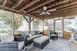 a screened porch with a couch and chairs and a ceiling fan at Retreat on the Island in Merritt Island