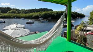 a hammock with a view of a river with boats at Casa Downtown in Caraíva