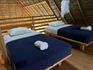 Dos camas en una cabaña de paja con toallas. en Hacienda Herrera Tambopata, en Puerto Maldonado