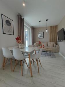 een woonkamer met een witte tafel en stoelen bij Apartament z 2 sypialniami - Nova Ludova - blisko 2 jezior in Biskupiec