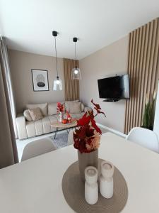 een woonkamer met een tafel met een vaas met bloemen bij Apartament z 2 sypialniami - Nova Ludova - blisko 2 jezior in Biskupiec