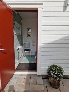 a red door of a house with a chair at Övernattningsrum i separat gästhus på Sävastön in Boden