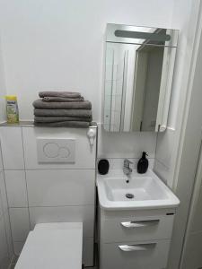 uma casa de banho branca com um lavatório e um espelho em Gemütliche 2-Zimmer Wohnung - Zentral - Netflix em Wuppertal