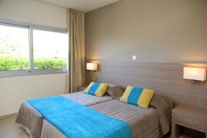 a bedroom with a bed with blue and yellow pillows at Makronisos Village in Ayia Napa