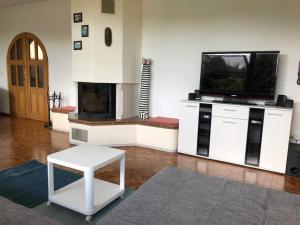 een woonkamer met een televisie en een witte tafel bij Apartmán s terasou a zahradou na cyklostezce 