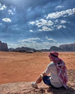 a man sitting on a rock in the desert at rum rema camp in Wadi Rum