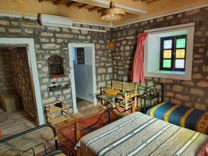 Cette chambre est dotée d'un mur en pierre avec un lit et une table. dans l'établissement Kasbah Imini Restaurant & Hotel, à Taourirt