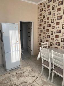 eine Küche mit einem Kühlschrank sowie einem Tisch und Stühlen in der Unterkunft 1 комнатная квартира в ЖК Арман в самом центре города in Aqtöbe