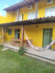 a yellow house with a hammock outside of it at Pousada Alto da Marina in Búzios