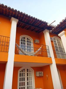 ein orangefarbenes Gebäude mit weißen Fenstern und einem Balkon in der Unterkunft POUSADA DAS FLORES in Porto Seguro