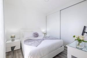 Dormitorio blanco con cama con pared de espejo en Villa Otto by GALMI, en Campanário