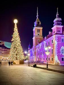 ein Weihnachtsbaum vor einem Gebäude in der Unterkunft Gold 5 fast WiFi 1 Gbs big 85'TV Netflix HBO Disney+ in Warschau