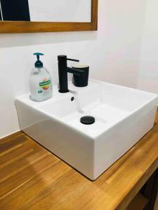 a white sink with a bottle of soap on it at Maisonnette avec terrasse in Argences +20 photos