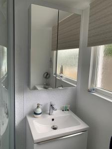 a white bathroom with a sink and a mirror at Chalet 80 in Sandown
