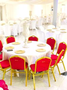 Habitación con mesas blancas y sillas rojas. en SILVERZB RESORT, en Iseyin
